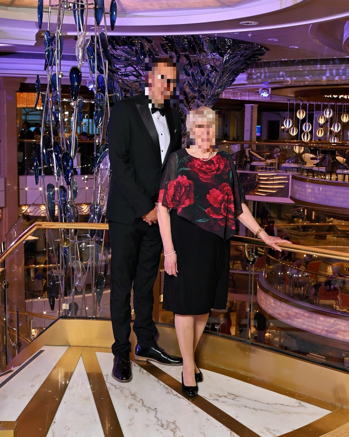 a mother and son in formal wear by a chandelier corridor