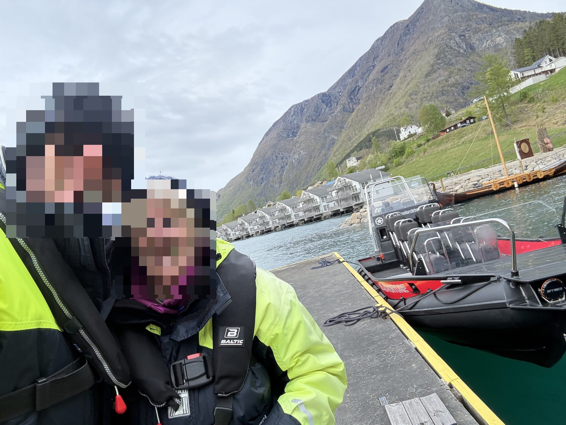 a mother and son at the dock, life vests on, polarcirkel RIB and viking longboats behind
